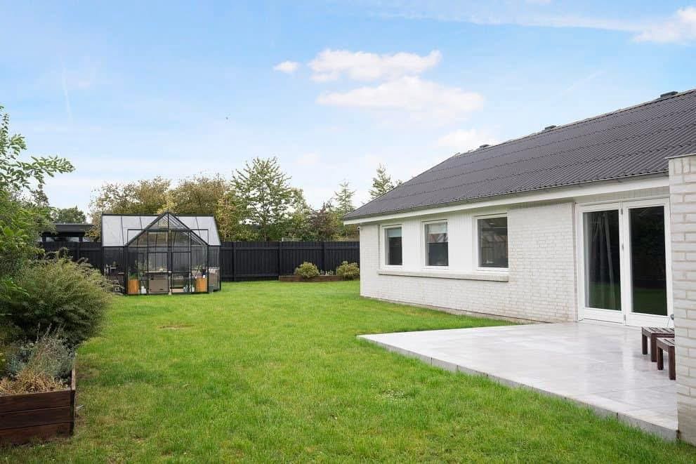 Have med græsplæne, drivhus og terrasse ved huset