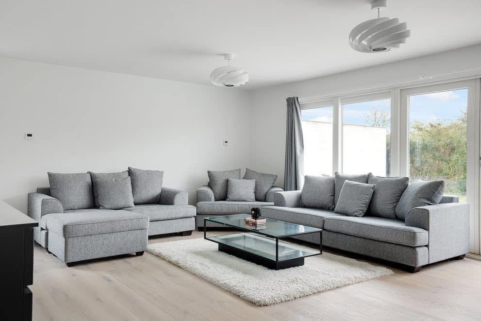 Lys stue med grå sofaer og glasbord